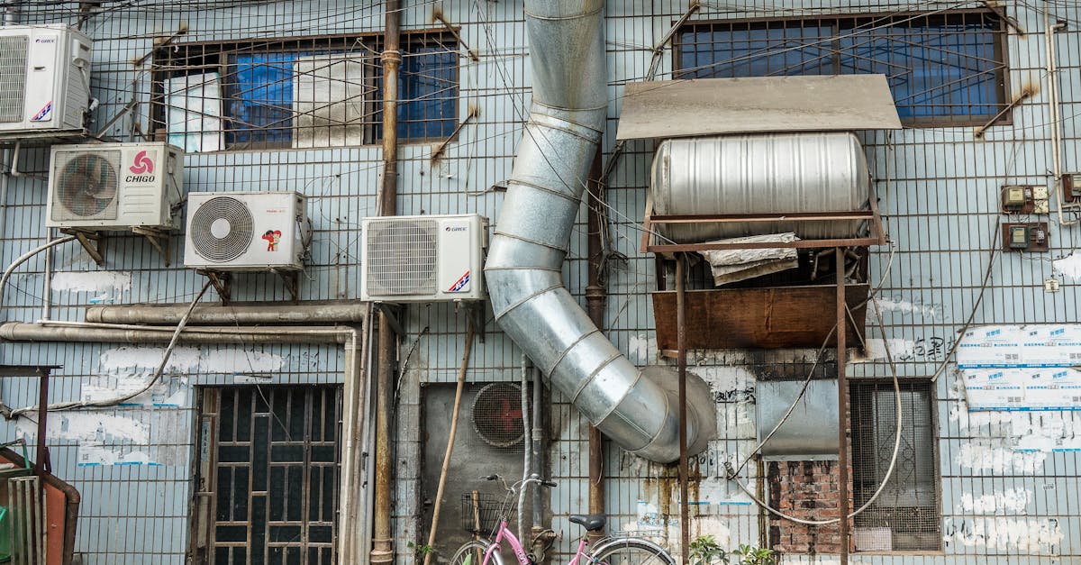An urban building facade featuring multiple air conditioning units and ductwork.