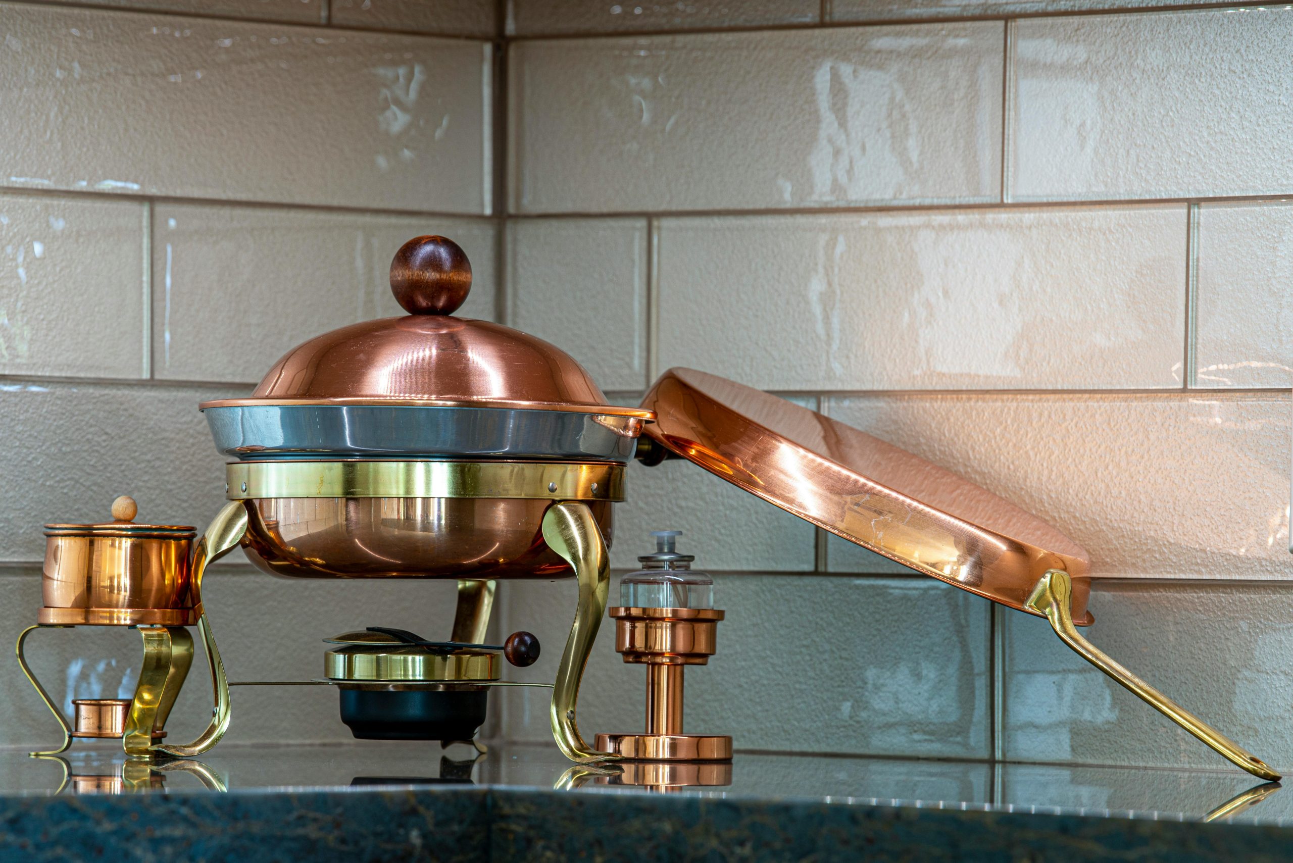 Stylish copper kitchenware set on a beige tiled countertop, perfect for upscale dining.